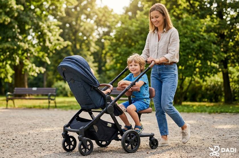 Starsze dziecko siedzące na dostawce z siedziskiem do wózka  podczas spaceru.